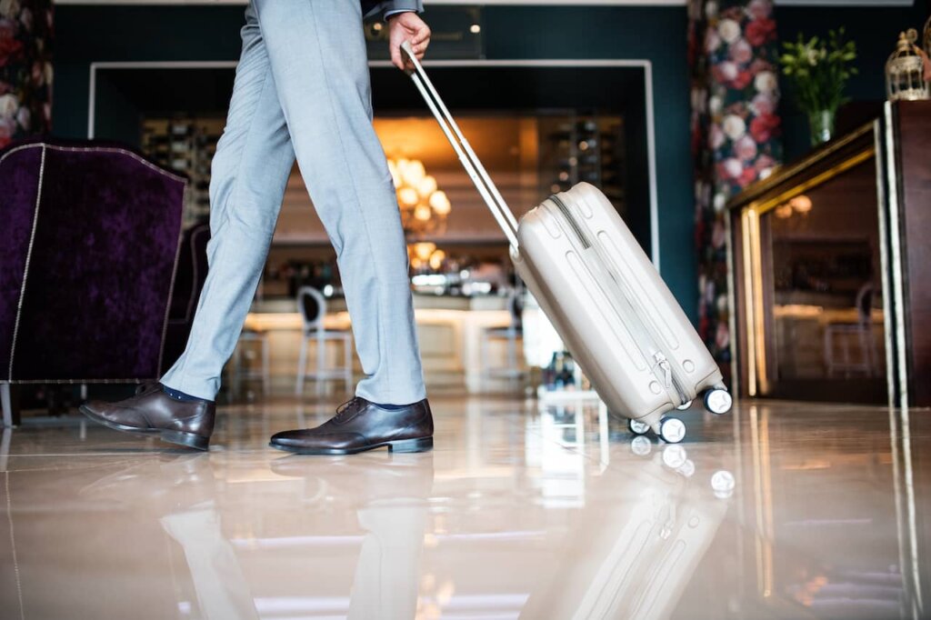 Businessman entering hotel with luggage.