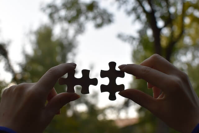 Two hands connecting two puzzle pieces